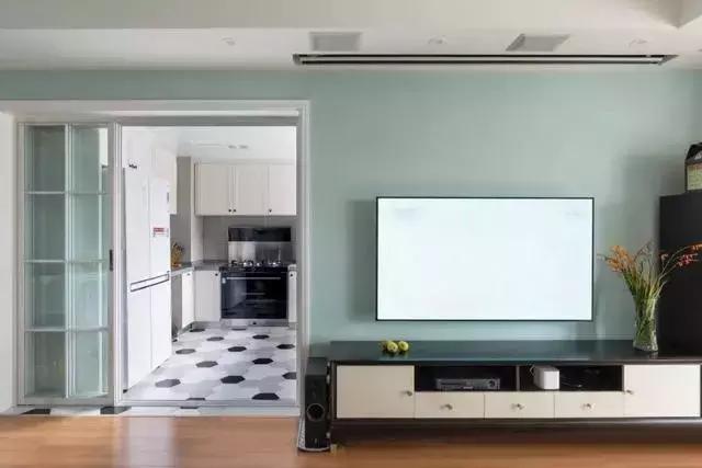 厨房的门是在客厅电视背景墙这边,用的是白框玻璃移门,与绿蓝色墙面