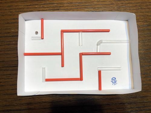 在妈妈的帮助下用吸管在纸盒里搭了一个简易迷宫