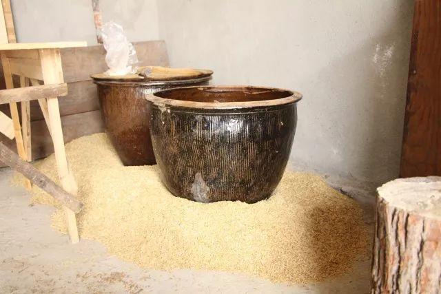 均匀的粮食装入酒坛里,置于小院一角,用谷壳堆在酒坛周围,烧火熏酒,等