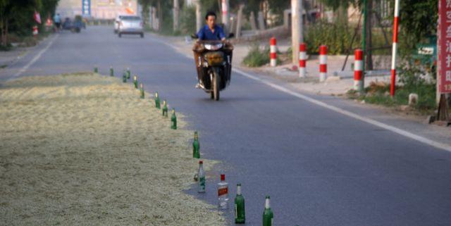 江西村民霸占公路晒粮路边摆满啤酒瓶有人车压爆胎
