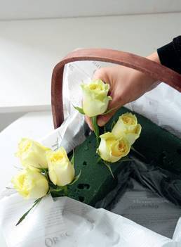 斜插入篮子里的花泥上,使花头朝篮外,3枝花呈现三角形