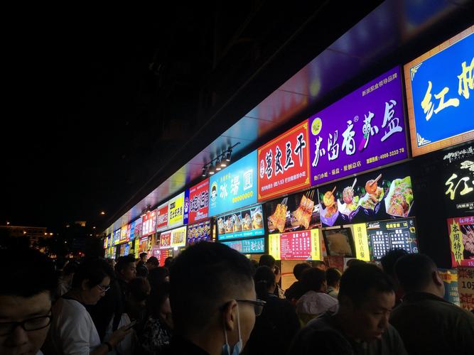 建设路的小吃街人潮拥挤,人们品尝着特色小吃.