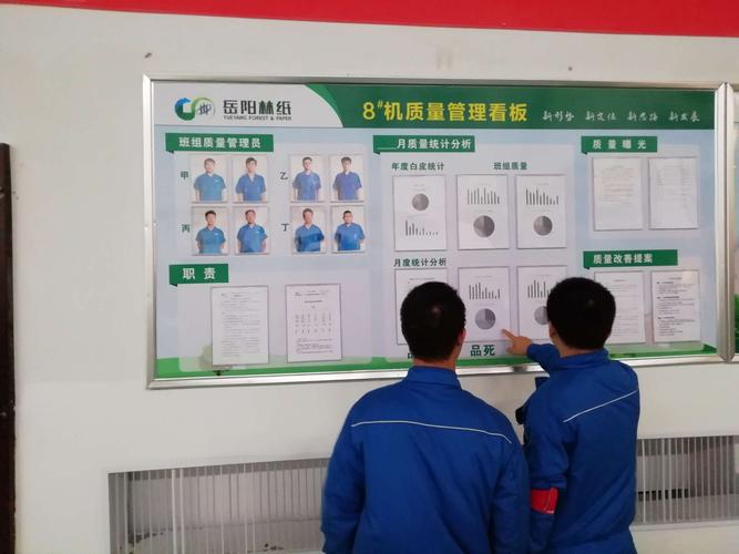 丁班工长张东军正在对照看板和班组质量管理员进行月度分析.