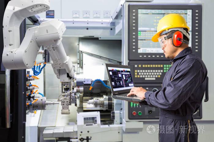 维修工程师使用笔记本电脑控制自动机械手与 cnc 机器在智能工厂.