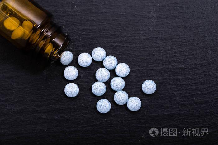 在一个瓶子里,药物止痛药的蓝色药丸.在黑色背景上的药物