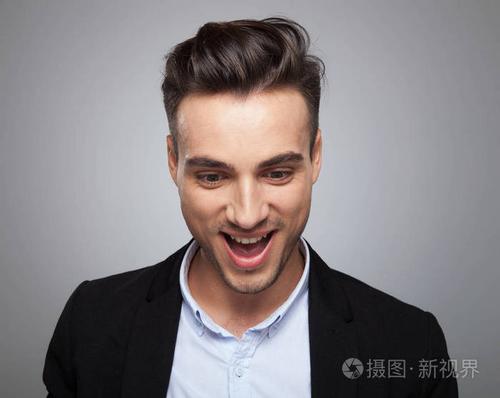 惊讶的休闲男子的肖像,张开嘴向下看,同时站在浅灰色的背景上