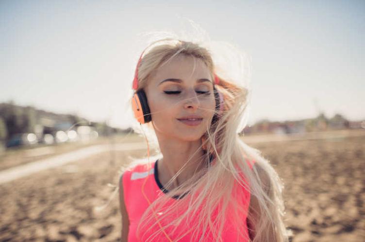 金发美女听音乐图片-在沙滩上享受音乐的放松的金发