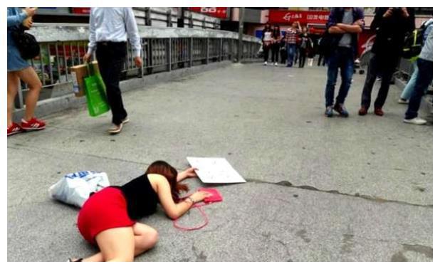 女子摔倒在地上路人经过却没人扶她只因她手中牌子上的八个字
