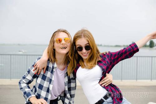 两个面带微笑的女性朋友在街上互相拥抱.假期,假期,爱情和友谊理念