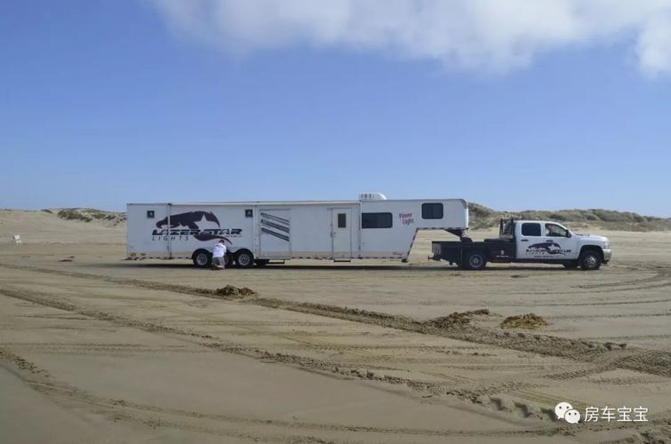 一辆超大型的拖挂房车,主人为了防止轮胎陷入沙坑,正在把车子上的每一