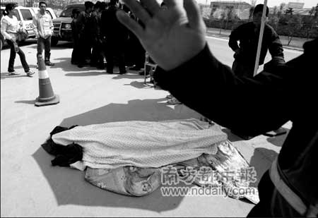 猝死者阿坚的尸体用被子遮盖着,停放在科技园门口.见习记者霍健斌摄
