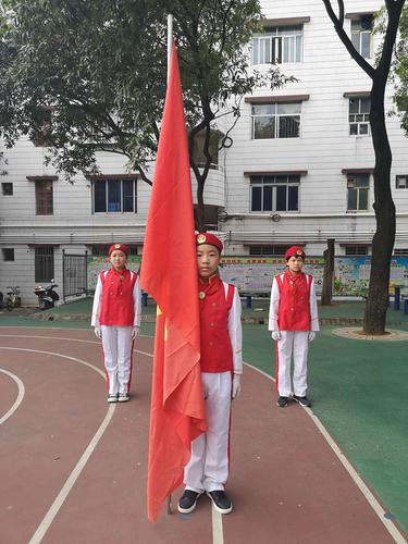 少先队旗手与护旗手迈着整齐的步伐,精神抖擞地进行着庄严的出旗仪式