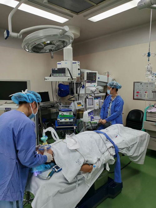 两位麻醉医师,在给病人做人工呼吸,面罩里是氧气.