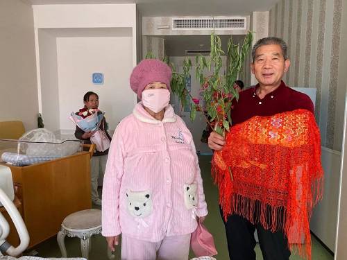 出院前,黄维平手拿桃树枝,与妻子和女儿一起拍照留念.