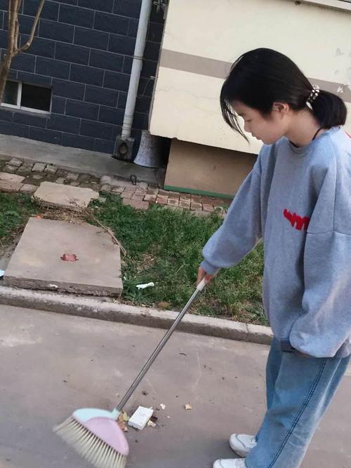 这是王玉琪同学,她在帮小区清洁工扫地,扫的很认真.