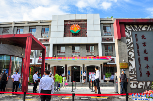 光明小学的老师在校门口迎接同学们重回校园.