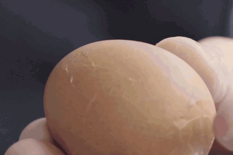 待鸡蛋降温,趁热手持鸡蛋以勺子敲碎蛋壳,裂纹要平均