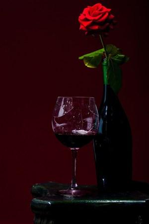 在红色玫瑰花旁边的红酒杯高清摄影图片