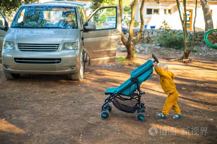 年轻的蹒跚学步的孩子在营地推婴儿车
