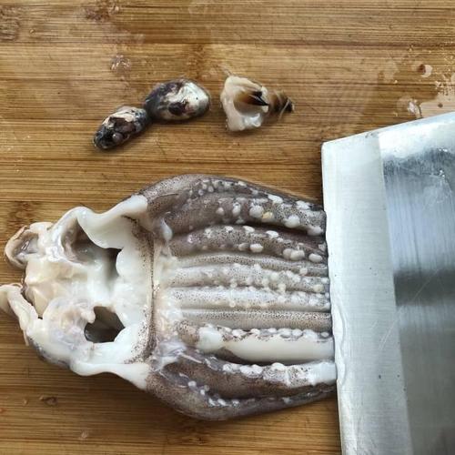 第3步,将鱿鱼头剖开,去掉牙齿和眼睛,把鱿鱼须上的硬壳吸盘全部刮掉.