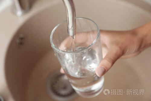 女人在厨房的特写镜头里往玻璃里倒水