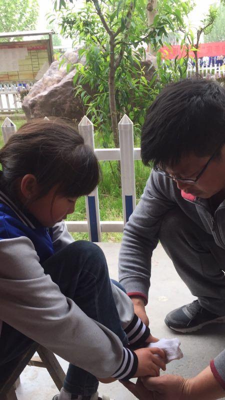 暖心的王校长亲自给孩子脱鞋脱袜,用手给孩子揉脚,对学生真切的关爱