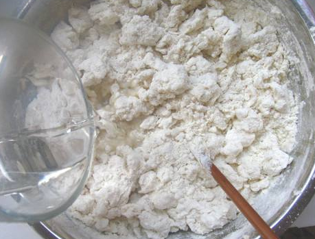 制作过程:第一步,300克面粉舀在和面盆中,分次少许的加上凉水,一边