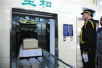 3月23日,北京市八宝山殡仪馆火化馆,工作人员将棺木放入火化口,并敬礼