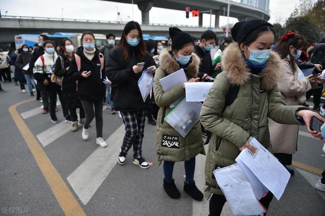 在南京林业大学考点,戴口罩的考生通过体温检测排队
