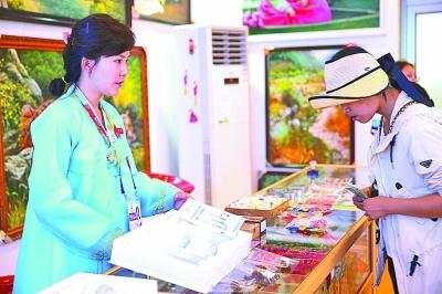 游客在朝鲜展馆购买特色产品.