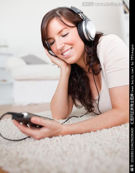 女人趴地毯上听音乐