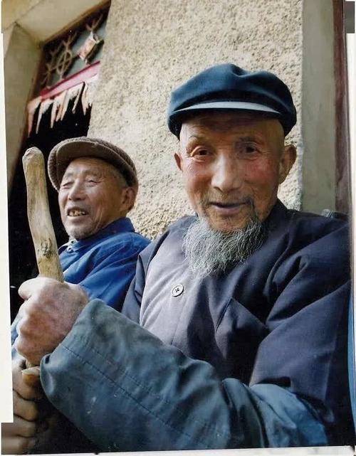 两个在门口晒照片的老爷爷