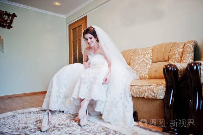 坐在床上的黑发新娘穿她的婚礼鞋子