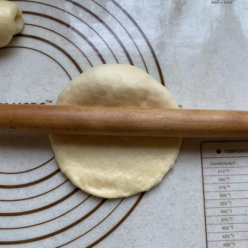 第9步,擀面棍轻压在面团上方,轻擀面团呈比较宽的长方形.