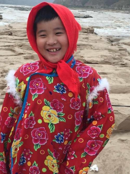 写美篇     在这图片上,有一个孩子,头戴鲜艳的红头巾,身穿红花棉袄