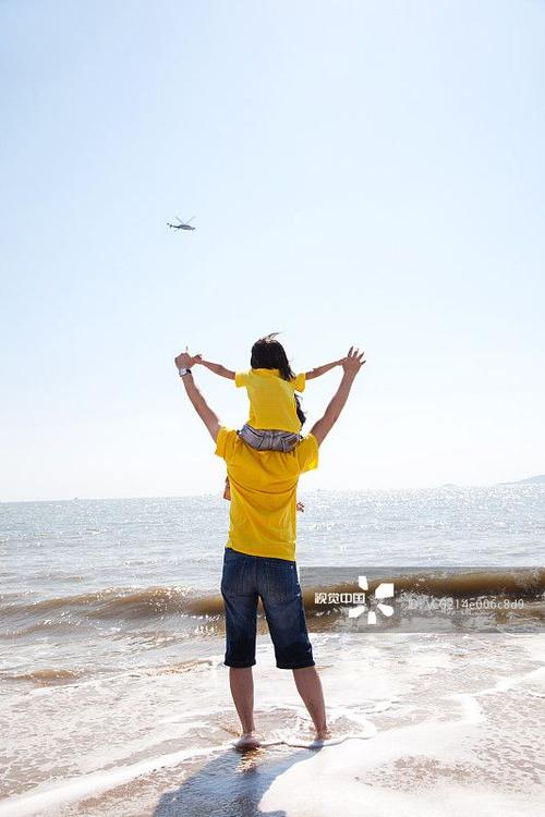女儿骑在爸爸肩膀站在沙滩上看远处_创意图片