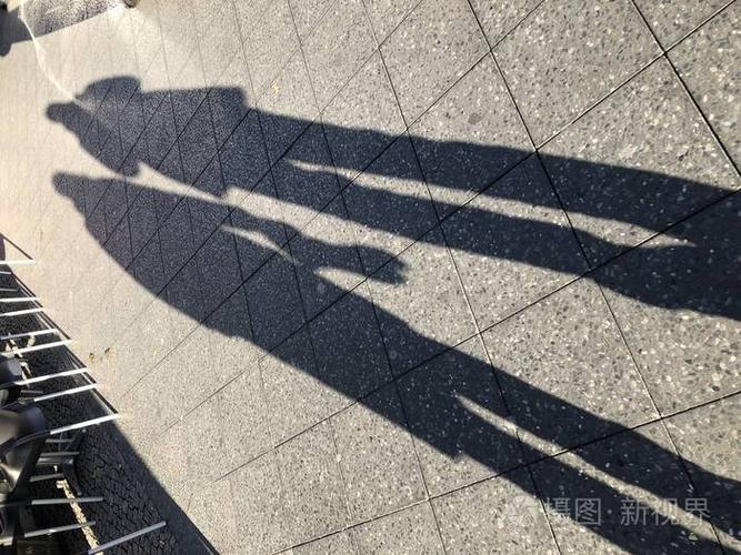 人行道上两个人的长长的影子. 明亮的黄昏太阳.