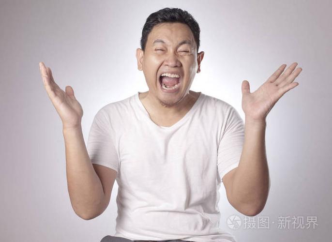 有趣的亚洲年轻人的肖像显示出胜利的姿态,张开嘴感到