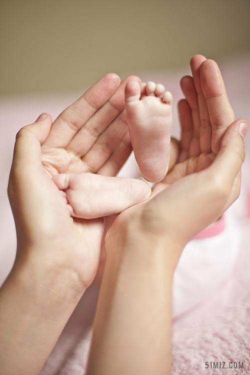 黄色人体娇小母亲捧着孩子的小脚丫脚丫亲子背景图片