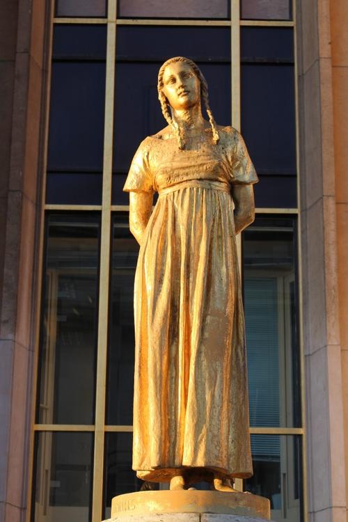 阳光照在金色少女雕像上,流金溢彩的少女更显迷人可爱,面带微笑的面庞