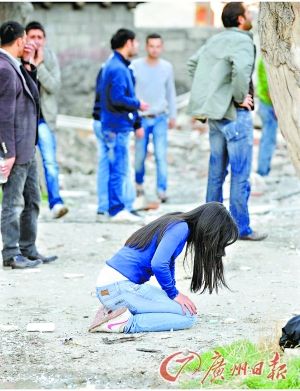 一名妇女在震后废墟中跪地痛哭