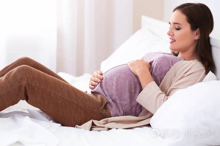 美丽的怀孕女人,躺在家里的床上