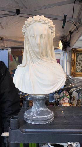 这尊雕塑描绘了一个蒙着面纱的新娘,头戴面纱(脸部清晰可见),面纱外面