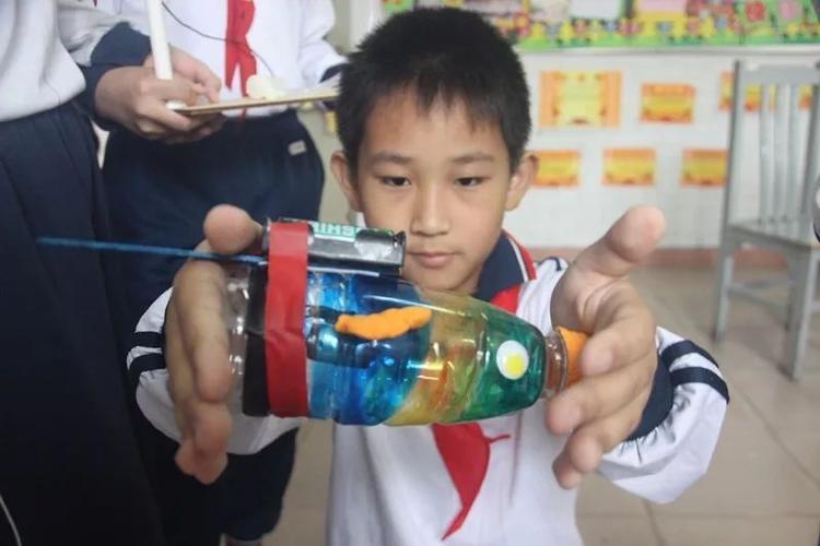 队长陈维轩向小e演示了他们小组设计的简易吸尘器,只见他一按下开关