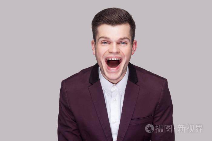 滑稽英俊的年轻人穿着紫罗兰色西装和白色衬衫,张开嘴