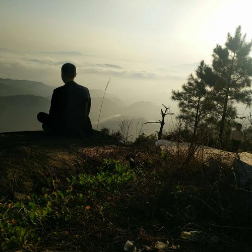 面对夕阳和连绵不绝的云海,静坐于巨石之上,也有些打坐参禅的意境