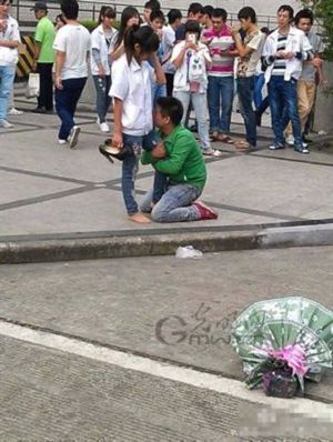 f1厂入口看到一个年轻男孩为追求女生,跪在地上抱住女孩大腿紧紧不放