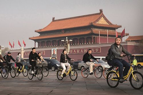 3月29日,北京,上班族们骑着共享单车经过天安门广场.