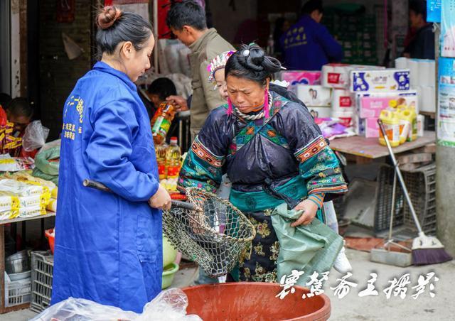 同样带着小孙子来赶场的大姐正在买鱼,小家伙在奶奶背上,正盯着网里的