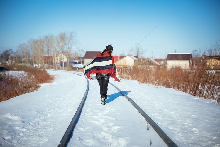 在冬天雪地铁轨上行走的女孩